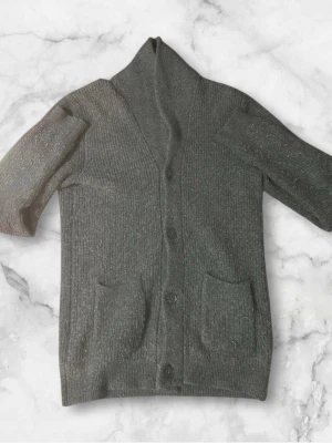 Mörkgrå kofta från Dressmann - Mysig mörkgrå kofta från Dressmann i ribbstickad ullmix. Koftan har knappar framtill, två fickor och en skön krage. Perfekt för lager på lager under kyliga dagar.