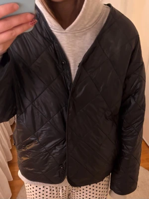 Svart quiltad pufferjacka - Gina Tricot - Säljer en svart quiltad pufferjacka med oversized passform. Jackan har tryckknappar framtill och har varit sönder på ena armen men är lagat nu och inget som syns! Jackan har använt sparsamt och är i mycket bra skick!