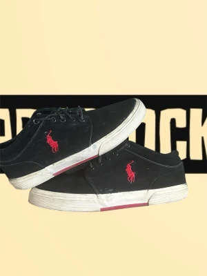 Svarta Polo Ralph Lauren sneakers - Svarta sneakers från Polo Ralph Lauren med röd broderad logga på sidan och vit sula med röd undersida. Skorna har snörning och en klassisk låg profil. Materialet är mocka och detaljerna är stilrena med rund tå och diskret Polo-märke på plösen.