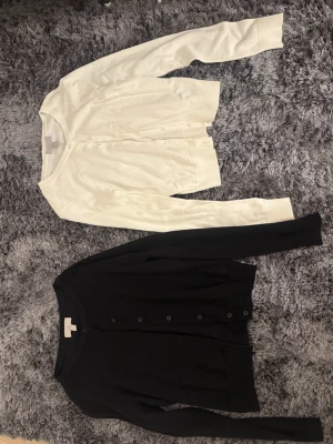Svart och vit kofta från H&M - Två klassiska koftor från H&M i storlek XS, en svart och en vit. Båda har rund hals, långa ärmar och knappar framtill, säljer båda för 130 kr! 