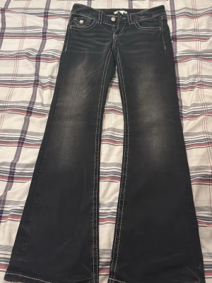 Svarta bootcut jeans Gina Tricot - Säljer ett par svarta bootcut jeans från Gina Tricot med kontrastsömmar i vitt. Klassisk femficksmodell och låg midja. Jeansen har dragkedja och knapp framtill och är tillverkade i ett stretchigt bomullsmaterial. 