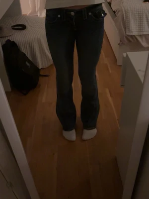 True religon  - Säljer ett par klassiska true religon  jeans i mörkblå tvätt. De har bootcut passform, normal midja och tydliga kontrastsömmar. Jeansen är i kraftigt jeanstyg och har den true religon -lappen bak. Perfekta för dig som gillar retrovibbar och tidlös stil.