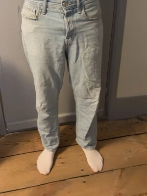 Ljusblå jeans Jack & Jones - Säljer ett par ljusblå baggy jeans från Jack & Jones, modell Baggy/Eddie. Klassisk femficksdesign, raka ben och avslappnad passform. Tillverkade i slitstarkt jeanstyg med snygga kontrastsömmar. Perfekta för en chill och avslappnad stil.