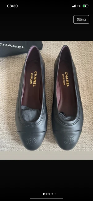 Svarta ballerinas från Chanel i skinn - Chanel ballerinas i svart skinn med rund tå och diskret CC-logga framtill. Insidan är vinröd och sulan har klassiskt rutmönster. Kommer med original dustbag. Perfekta för dig som gillar tidlös och lyxig stil.