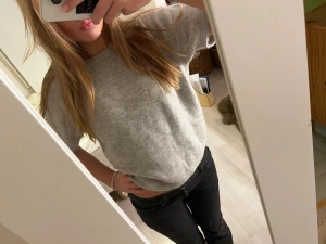 Grå stickad topp från Gina Tricot - Säljer en enkel och snygg grå stickad topp från Gina Tricot. Modellen har korta ärmar, rund hals och är i en loose passform. Perfekt att matcha med jeans eller kjol för en chill look. Materialet är mjukt och skönt stickat.