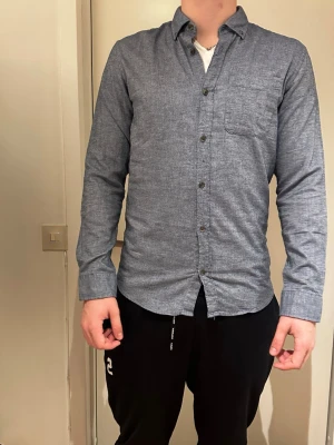 Mörkgrå skjorta i bomullsflanell - Snygg mörkgrå skjorta från Selected Homme i mjuk bomullsflanell. Klassisk krage, bröstficka och knappar framtill. Perfekt till jeans eller chinos för en clean look.