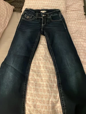 Mörkblå jeans från Gina Tricot - Snygga mörkblå jeans från Gina Tricot med kontrastsömmar och klassisk femficksdesign. Jeansen har raka ben och normal passform, tillverkade i slitstarkt denimtyg. Perfekta för dig som gillar en enkel men ändå detaljerad look.