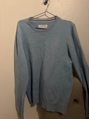 Ljusblå stickad tröja från Pier One - En stilren ljusblå stickad tröja från Pier One. Tröjan har rund halsringning, ribbade muddar vid ärmslut och nederkant samt lång ärm. Perfekt för lager på lager under kyligare dagar.