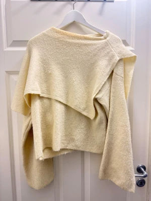 Beige asymmetrisk stickad tröja Zara - Säljer en beige stickad tröja från Zara i storlek M. Tröjan har en unik asymmetrisk design med breda ärmar och en oversized passform. Perfekt för dig som gillar statement-plagg och vill ha något extra i garderoben.