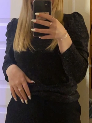 Svart glittrig långärmad topp - Står i tröjan att det är xl, men den passade mig perfekt när jag var strl S.     Säljer en svart långärmad topp med glittriga detaljer och lätt puffade axlar. Toppen har en rund halsringning och är gjord i ett stretchigt material som ger en snygg passform. 