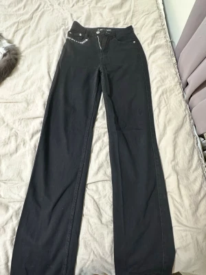 Svarta jeansbyxor med tryck från FB SISTER - Svarta jeansbyxor från FB SISTER med raka ben och hög midja. På framsidan står det 'BUY ME A TICKET TO...' och på bakfickorna är det stort vitt tryck med texten 'LOS ANGELES'. Klassisk femficksmodell i bomull med dragkedja och knapp.