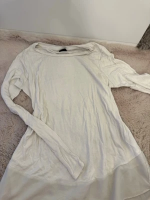 Vit långärmad topp med meshdetalj - Säljer en enkel och stilren vit långärmad topp med rund halsringning. Toppen har en snygg meshdetalj längst ner som ger en extra touch. Perfekt att styla med jeans eller kjol för en clean look.