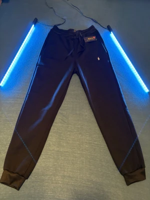 Svarta mjukisbyxor Polo Ralph Lauren - Svarta mjukisbyxor från Polo Ralph Lauren med dragsko i midjan och klassisk broderad logga på benet. Byxorna har ribbade muddar vid bensluten och är tillverkade i mjukt bomullsmaterial för maximal komfort. Inte för vuxna! Titta på min andra annons där är frakten gratis 