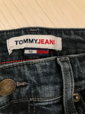 Tommy Hillfiger jeans plus ett år på köpet  - Här får du 2 för 1. Det mörkare paret är av märket Tommy Jeans och de ljusare som medföljer är av märket &Denim och modellen är Regular Tapered Cropped. Storlek 32 x 32