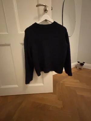 Mörkblå stickad tröja Gina Tricot - Mysig mörkblå stickad tröja från Gina Tricot i storlek 134/140. Tröjan har en enkel, klassisk design med rund hals och långa ärmar. Perfekt för kyliga dagar och lätt att matcha med olika outfits.