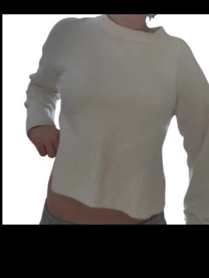 Vit stickad tröja från & Other Stories - Säljer en enkel och stilren vit stickad tröja från & Other Stories Paris Atelier. Tröjan har en croppad passform, rund halsringning och ribbade muddar vid ärmslut och nederkant. Perfekt till jeans eller kjol för en clean look.