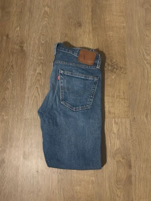 Levi's Premium 511 blå jeans - Säljer ett par klassiska Levi's Premium 511 jeans i blå tvätt. Jeansen har fem fickor, raka ben och normal passform. Bredd 39 cm / längd 98 cm.