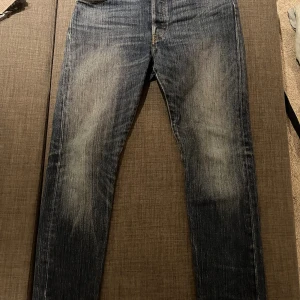 Levi's 501 jeans i mörkblå denim - Klassiska Levi's 501 jeans i mörkblå tvättad denim med snyggt slitna detaljer på låren och knäna. Bra passform, femficksmodell och ikonisk läderpatch bak i midjan. Perfekta för dig som gillar tidlös stil och vill ha ett par jeans som funkar till allt. W29 L30