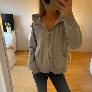 Grå hoodie från Crancotton XXL - Grå hoodie med dragkedja från Crancotton i storlek XXL. Tröjan har huva med snörning, två stora fickor framtill och ribbade muddar vid ärmslut och nederkant. Tillverkad i mjuk bomullsmix, perfekt för chill dagar.