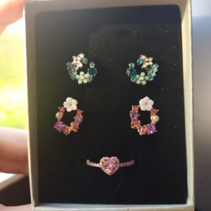 Set med örhängen och ring Strl 8(57) - Supergulligt smyckeset med två par örhängen och en ring. Ringen är roséguldfärgad med ett rosa hjärta av glittrande stenar. Material : koppar 