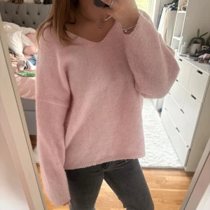 Ljusrosa stickad tröja med v-ringning - Supermysig ljusrosa stickad oversiezed tröja med v-ringad hals och långa ärmar. Tröjan har en loose fit. Mjuk och fluffig känsla, passar perfekt till jeans eller kjol. 