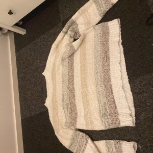 Randig stickad tröja från SHEIN - Mysig stickad tröja från SHEIN i storlek L. Tröjan har breda horisontella ränder i vitt, beige, grått och ljusbrunt. Den är långärmad och har en avslappnad passform, perfekt för kyliga dagar. Superenkel att styla med jeans eller kjol.