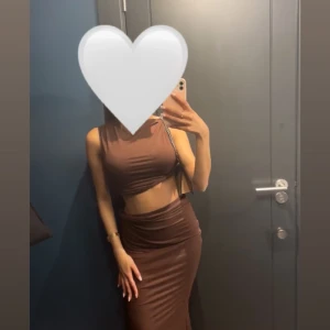 Brun set  - Säljer en brun långklänning med ärmlös design och tight passform. Klänningen har en croppad topp och hög midja, vilket ger en modern och trendig look. Perfekt för dig som vill sticka ut med en stilren och cool outfit.