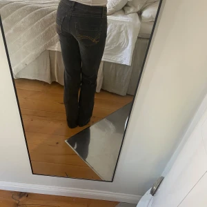 Svarta bootcut jeans - Säljer ett par svarta jeans med bootcut-modell och snygga kontrastsömmar på bakfickorna. Slutsålds jeans med låg midja.