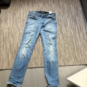 Ljusblå jeans från Jack & Jones - Säljer ett par ljusblå jeans från Jack & Jones med klassisk femficksdesign och snygga slitningar framtill. Jeansen har rak passform och är tillverkade i mjuk bomullsdenim. Perfekta för en avslappnad och trendig look. Den ända effekten är att högra fickan är trasig men går nog att laga. W31 L34