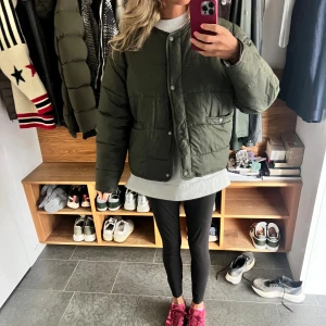 Olivgrön quiltad pufferjacka Zara - Säljer en olivgrön pufferjacka med quiltad design och rund hals. Jackan har tryckknappar framtill och två fickor med lock. Modellen är loose fit och har långa ärmar. Perfekt för dig som gillar en chill och trendig look.