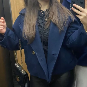 Mörkblå kappa med knappar - Snygg mörkblå kappa och den är kort men inte för kort. Jackan har en loose passform och är tillverkad i ett ull-liknande material. Perfekt för dig som vill ha en stilren. Har använt den få gånger då jag tycker den är för lite för mig tyvärr 