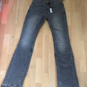 Grå flared jeans helt nya - Säljer ett par grå jeans från boohooMAN med raka ben och klassisk femficksdesign. Jeansen har en snygg tvättad look och är tillverkade i jeansmaterial. Passar dig som gillar en enkel och stilren vibe.