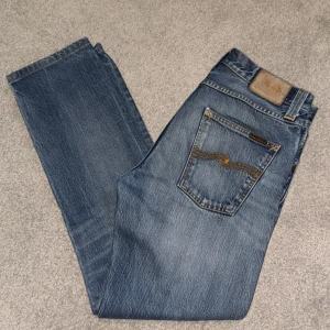 Blå jeans från Nudie Jeans - Snygga blå jeans från Nudie Jeans med klassisk femficksdesign och kontrastsömmar på bakfickan. Jeansen har en rak passform och är tillverkade i slitstarkt denim. Perfekta för dig som gillar en tidlös och avslappnad stil.
