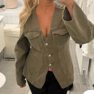 Olivgrön jeansjacka med v-ringning - Säljer en olivgrön jeansjacka från Gina Tricot markerad midja. Ny med prislapp.