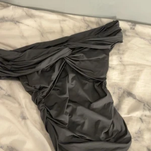 Svart offshoulder topp Bik Bok - Supersnygg svart offshoulder topp från Bik Bok med draperad och twistad detalj framtill. Tight passform och kort längd, perfekt för dig som gillar trendiga och stilrena plagg. Materialet är mjukt och stretchigt för en bekväm känsla.