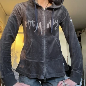 Grå velourhoodie Odd Molly - Mysig grå hoodie från Odd Molly i mjuk velour med dragkedja framtill, huva med snören och broderad logga på ärmen. Snyggt tryck över bröstet och ribbade muddar vid ärmslut. Perfekt för chill dagar och enkel att styla med jeans.