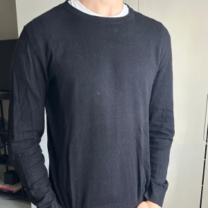 Svart stickad tröja  - En enkel och stilren svart stickad tröja med rund hals och långa ärmar. Perfekt för dig som gillar klassisk och clean stil. Storlek M. Modellen är 190cm, 78kg. Skriv om du har några frågor:)
