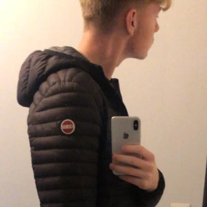 Svart pufferjacka från Colmar - Säljer en svart pufferjacka från Colmar i storlek S men kan passa M med huva och klassisk logga på ärmen. Jackan är quiltad och har dragkedja framtill. Perfekt för kyliga dagar och riktigt snygg till streetwear-grisch och till och med archive stilen. Jag säljer pga att den är lite för kort för min smak.  Går ner i pris vid snabb affär🙂 Bara att skriva om fler bilder eller annan information. 