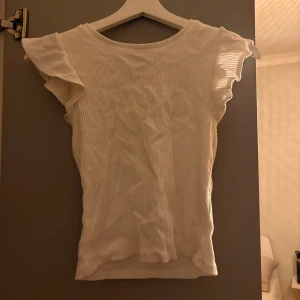 T-shirt med volanger - T-shirt med volanger på ärmarna. Ribbat och stretchiga material. Storlek M men passar även mig med xs