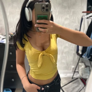 Gul ribbad croppad topp med knyt - Säljer en ljusgul ribbad croppad topp med korta ärmar och snygg knytning framtill. Toppen har djup v-ringning och sitter tight. Superfin till jeans eller kjol!