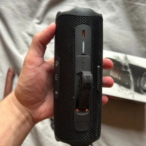 JBL Flip 7 - JBL Flip 7 bärbar Bluetooth-högtalare i mycket fint skick. Kraftfullt ljud, vattentålig design och lång batteritid. Levereras med originalkartong, laddkabel, karbinhake och snabbstartsguide. Perfekt för både inomhus och utomhusbruk.
