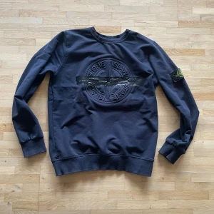 Stone Island sweatshirt - Säljer en mörkblå sweatshirt från Stone Island i storlek S. Tröjan har det klassiska broderade logotypmärket på ärmen och en stor Stone Island-logga på bröstet. Tillverkad i mjuk bomull med ribbade muddar och rund hals. Perfekt för en clean och stilren look.
