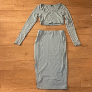 Ljusblå kjol plus topp - Säljer en ljusblå ribbad medel lång kjol med  en cropped topp från SHEIN i storlek S. Kjolen är figurnära och har en enkel, stilren design utan synliga detaljer. Materialet är mjukt och stretchigt, perfekt för en trendig look. 