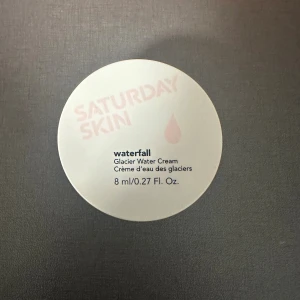 Saturday Skin Waterfall Glacier Water Cream - En söt, rund burk med 8 ml återfuktande ansiktskräm från Saturday Skin. Waterfall Glacier Water Cream har en lätt, gel-liknande formula och kommer i en ljusrosa plastburk. Perfekt för dig som vill ha en fräsch och återfuktad känsla.
