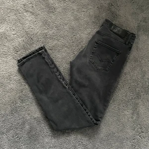 Replay Jeans - Svarta jeans från Replay med klassisk femficksdesign och smal passform. Jeansen har en diskret logotyp på bakfickan och är tillverkade i stretchigt denimtyg för extra komfort. Perfekta för dig som gillar en stilren och enkel look.