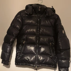 Mörkblå moncler Maya - Hejsan! Jag säljer nu denna riktigt feta moncler Maya i storlek 0 vilket motsvara xs. Den ör i bra skick men tidningen i jackan har tyvär åkt av! Annars har den inga defekter. Har kvitto! Hör av er om ni har frågor!😀