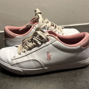 Vita och rosa sneakers från Polo - Snygga vita sneakers från Polo Ralph Lauren med rosa detaljer och glittrig häl, snörena tvättas innan postning! Storlek 38, man kan se att dom är använda därför ett lägre pris!