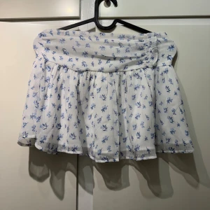 Vit blommig kortkjol från Gina Tricot - Supersöt vit kortkjol från Gina Tricot med blått blommönster. HELT NY!!!! Storlek 146-152 Skriv för mer bilder och frågor så svarar jag så fort jag kan pris går altid att diskuteras💕💕