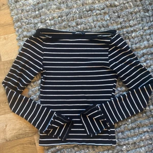 Svartvit randig långärmad topp Gina Tricot - Säljer en svart långärmad topp från Gina Tricot med vita horisontella ränder. Toppen har en klassisk, smal passform och är tillverkad i mjuk bomull. Perfekt för dig som gillar enkel och stilren design med lite edge.