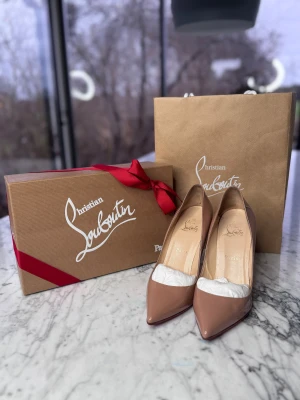 Christian Louboutin Nude Heels - Snygga nude pumps från Christian Louboutin med klassisk röd sula och spetsig tå. Skorna har hög klack och är tillverkade i glansigt lackat skinn. Mina bröllopsskor inköpta i NYC och tyvärr för små för mig nu. 